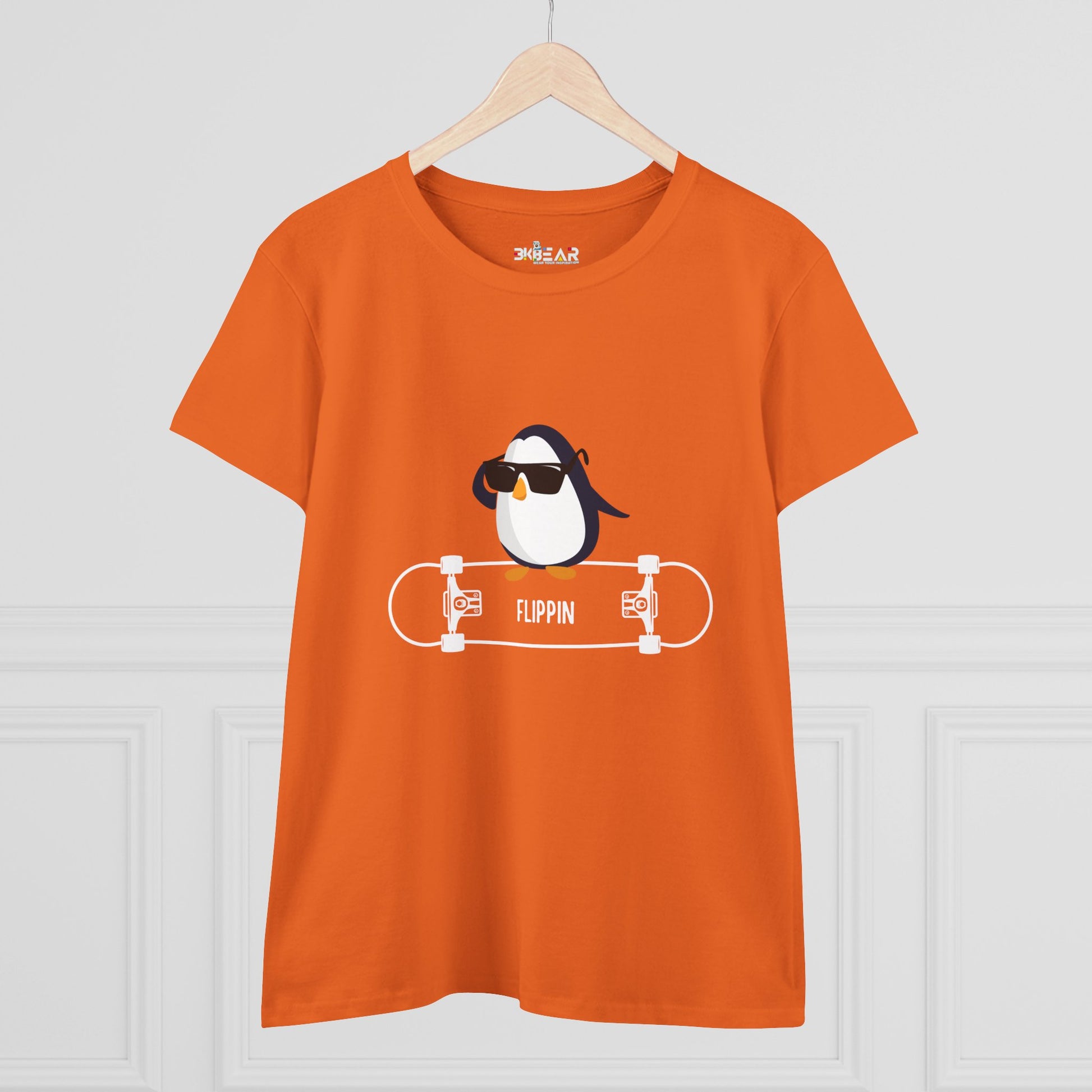 Orange Adélie penguin tee featuring a penguin with sunglasses on a skateboard graphic