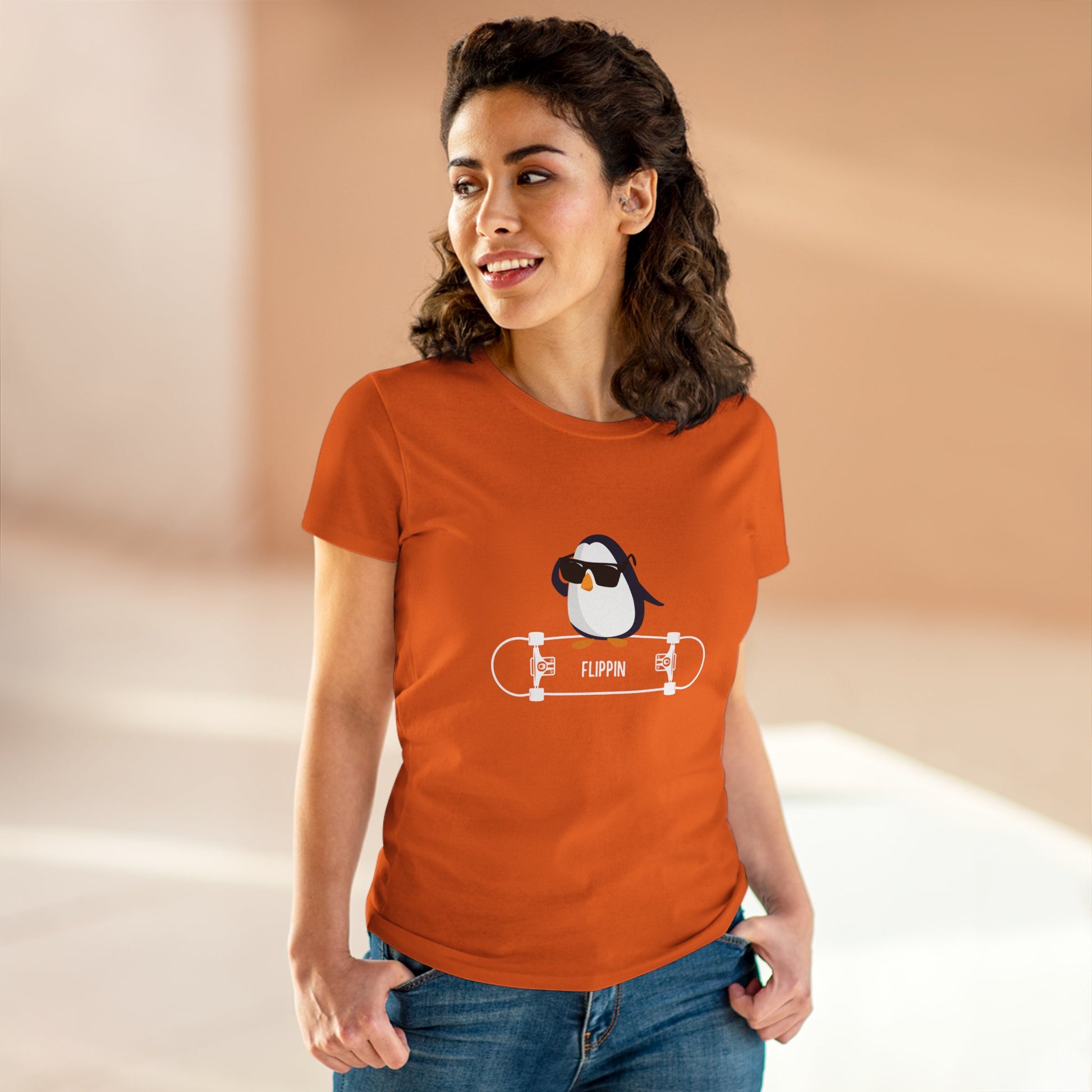 Woman wearing an orange Adélie penguin tee with a cool penguin graphic on a skateboard