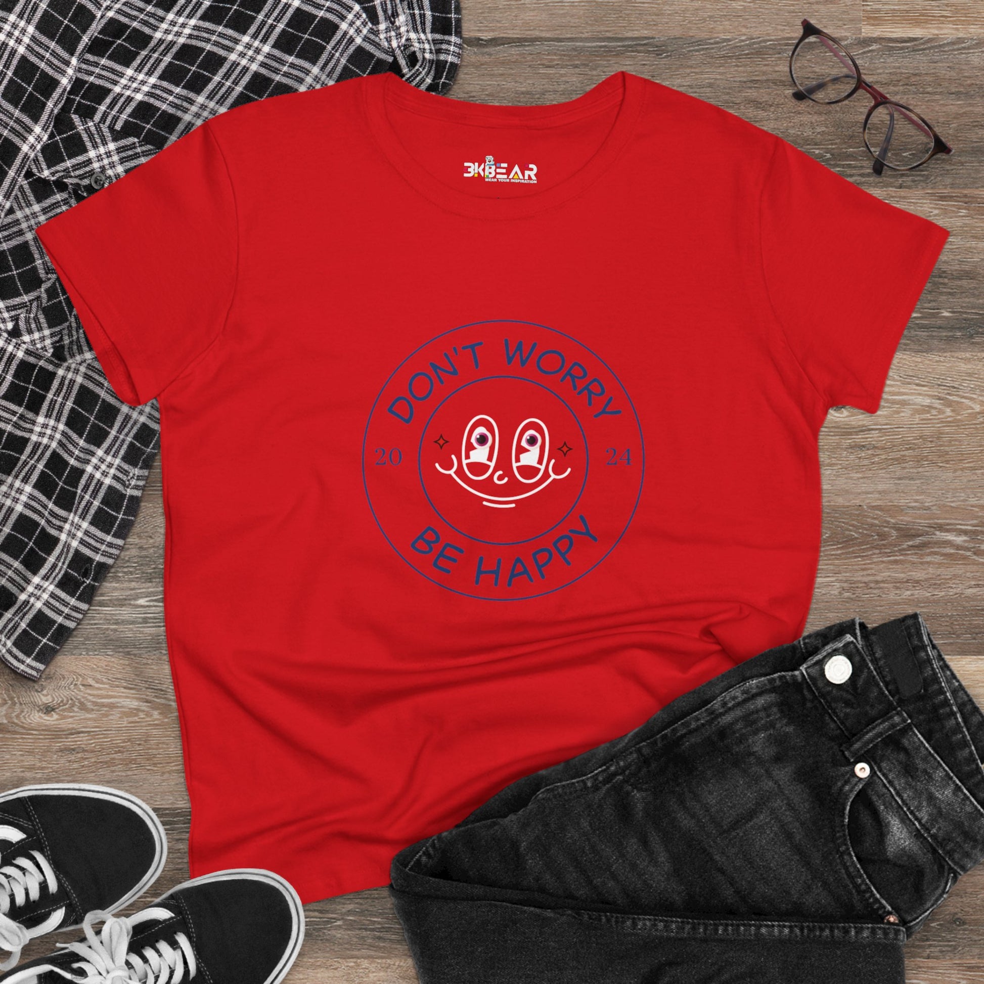 Red don’t worry be happy t-shirt with smiley face graphic laid out with black jeans and black sneakers