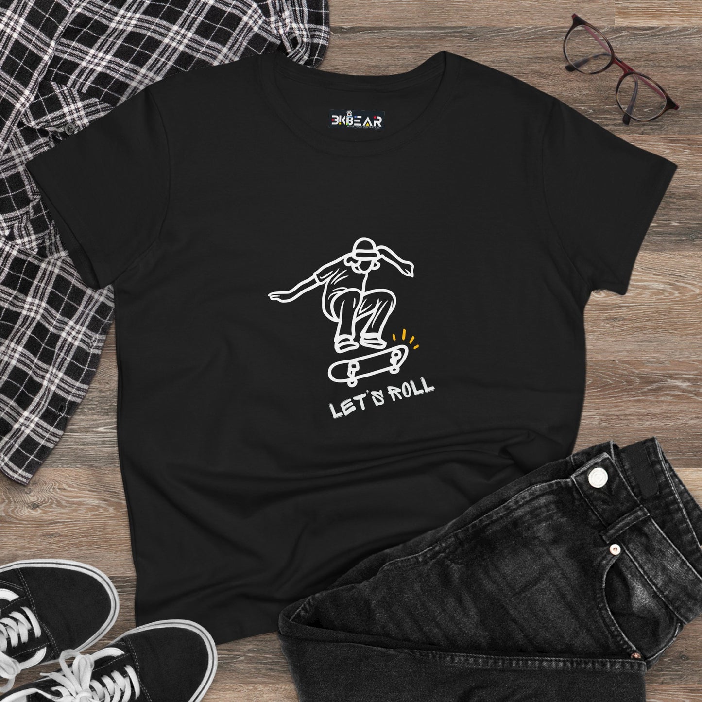 Black Let’s Roll shirt with white skateboarder graphic laid out with jeans and sneakers