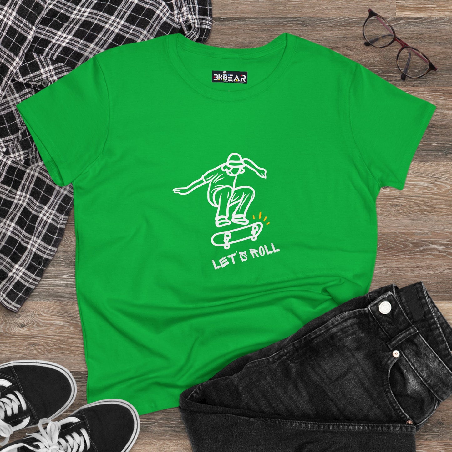 Green Let’s Roll shirt with skateboarder graphic laid flat with jeans and sneakers