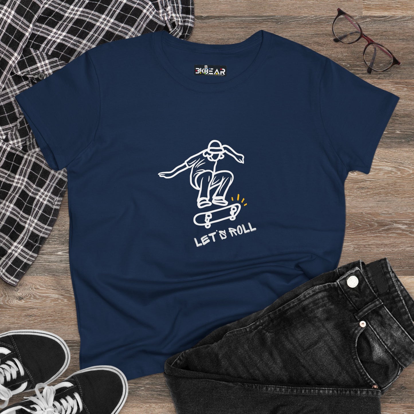 Navy blue Let’s Roll shirt with white skateboarder graphic laid flat with black jeans and sneakers