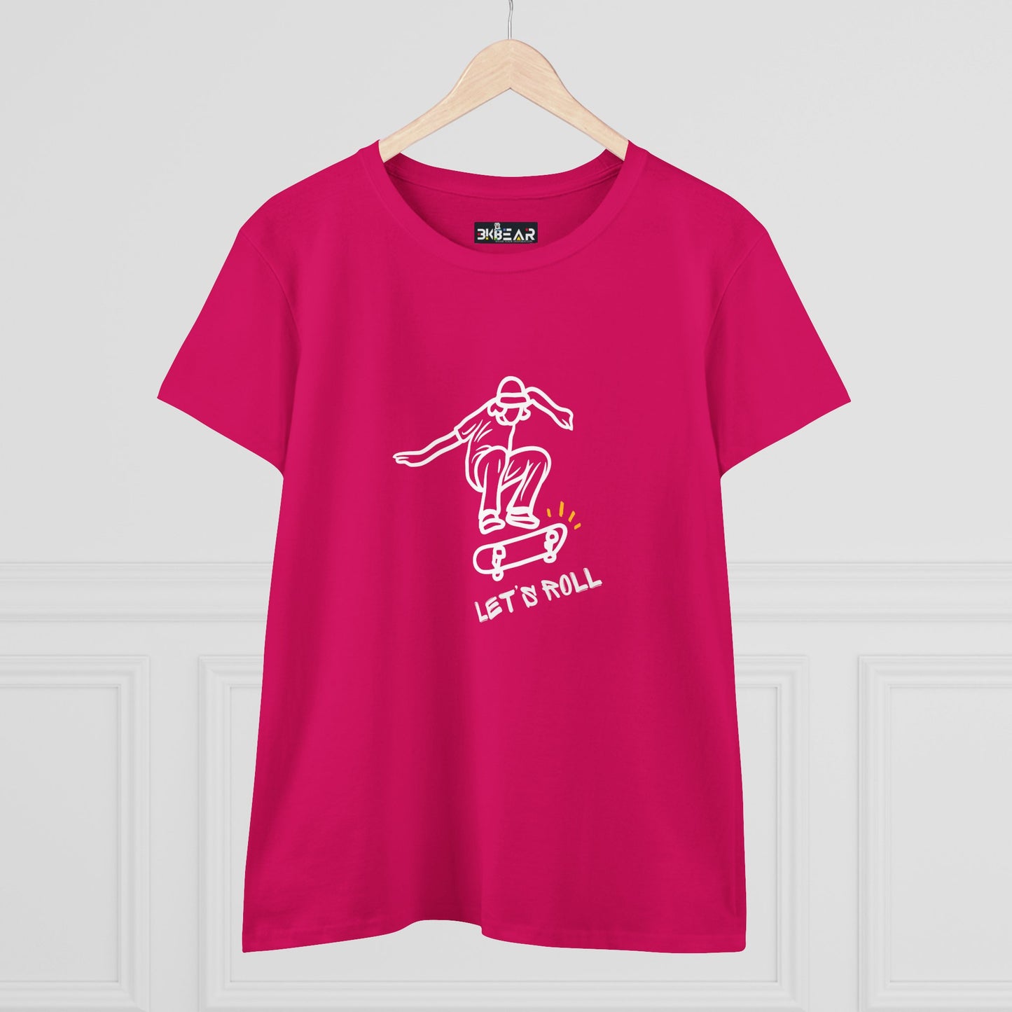 Pink Printify Let’s Roll shirt with white skateboarder graphic hanging on wooden hanger