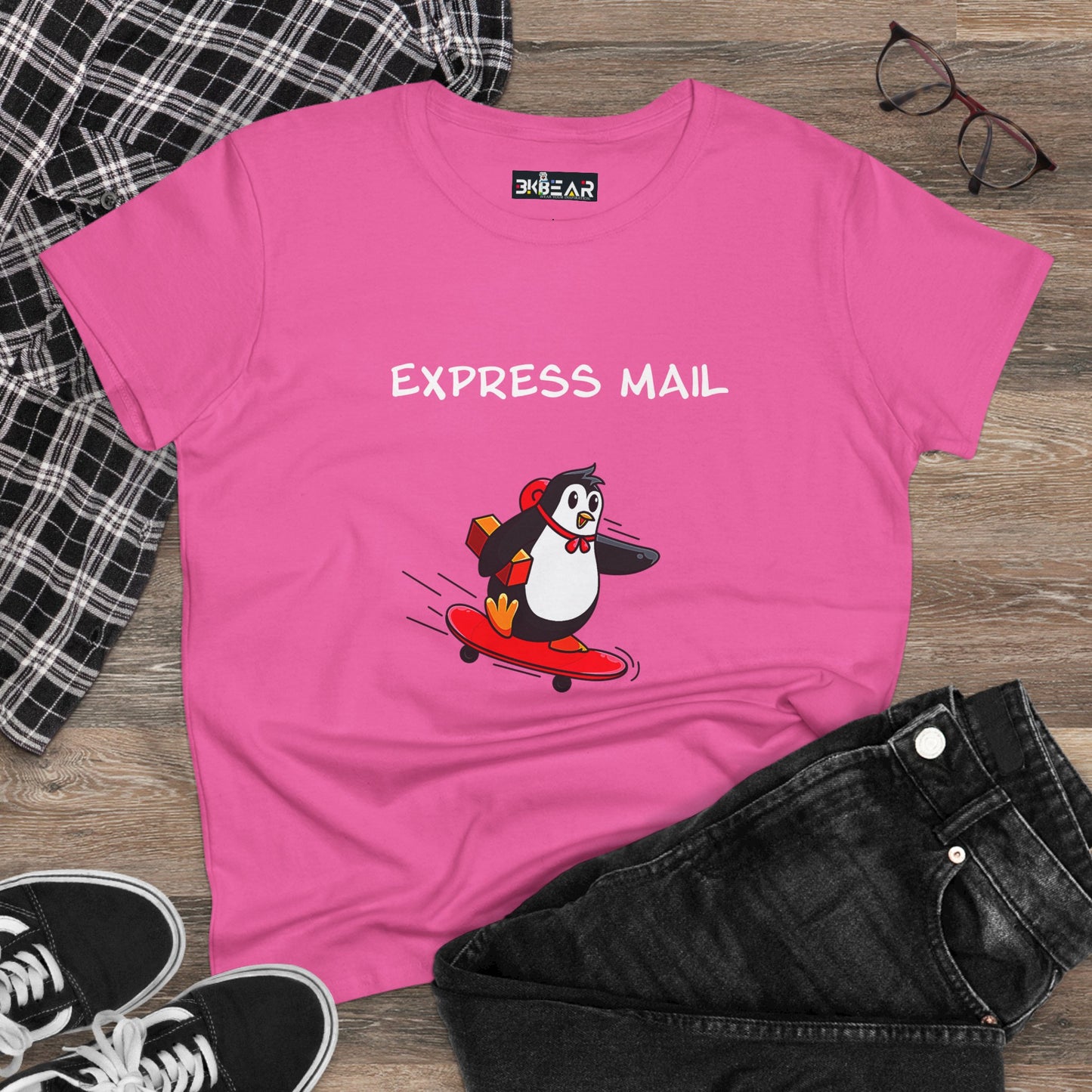 Pink penguin graphic tee with express mail design on skateboard, laid flat with black jeans and sneakers