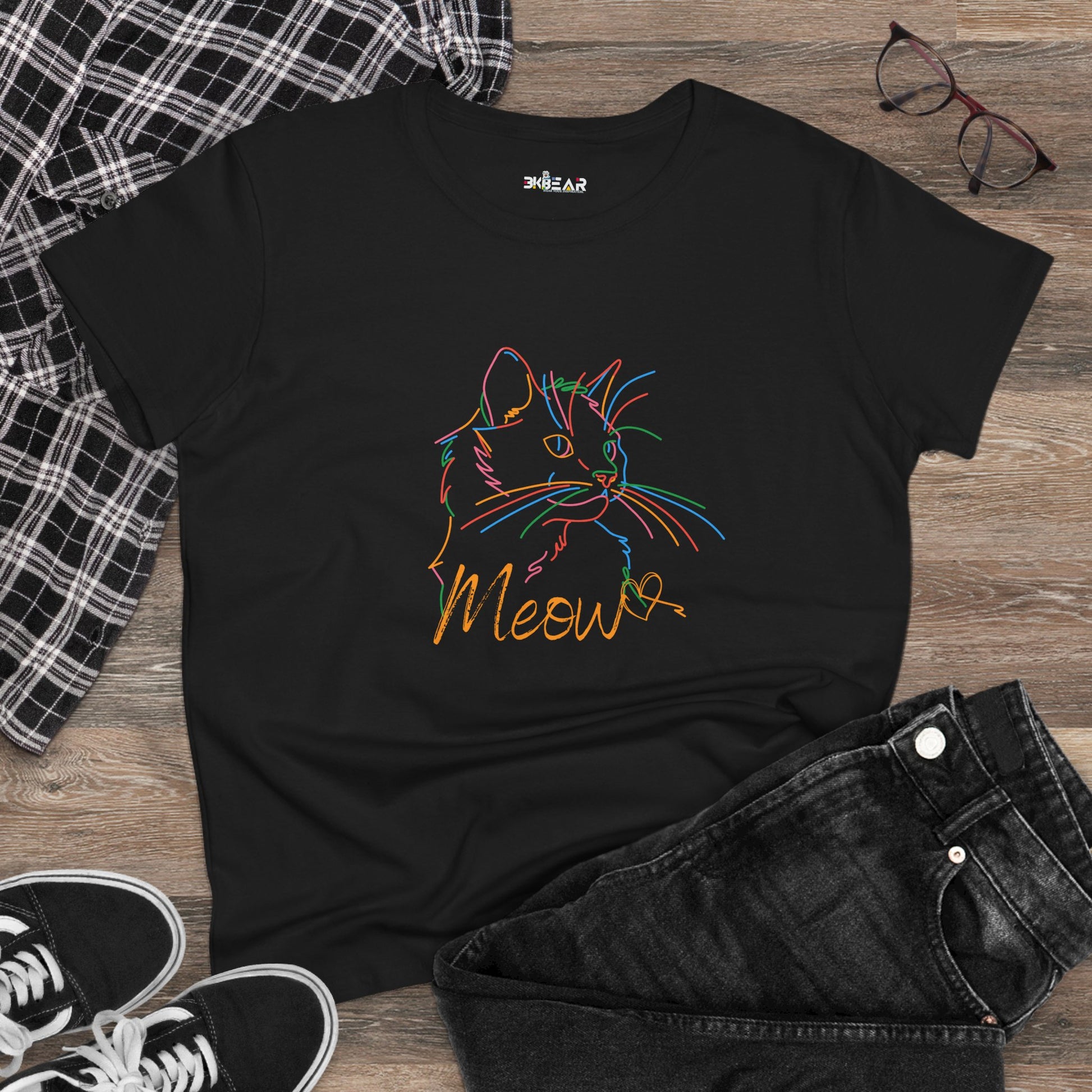 Black Printify t-shirt with colorful cute cat print tee and the word Meow on wooden floor