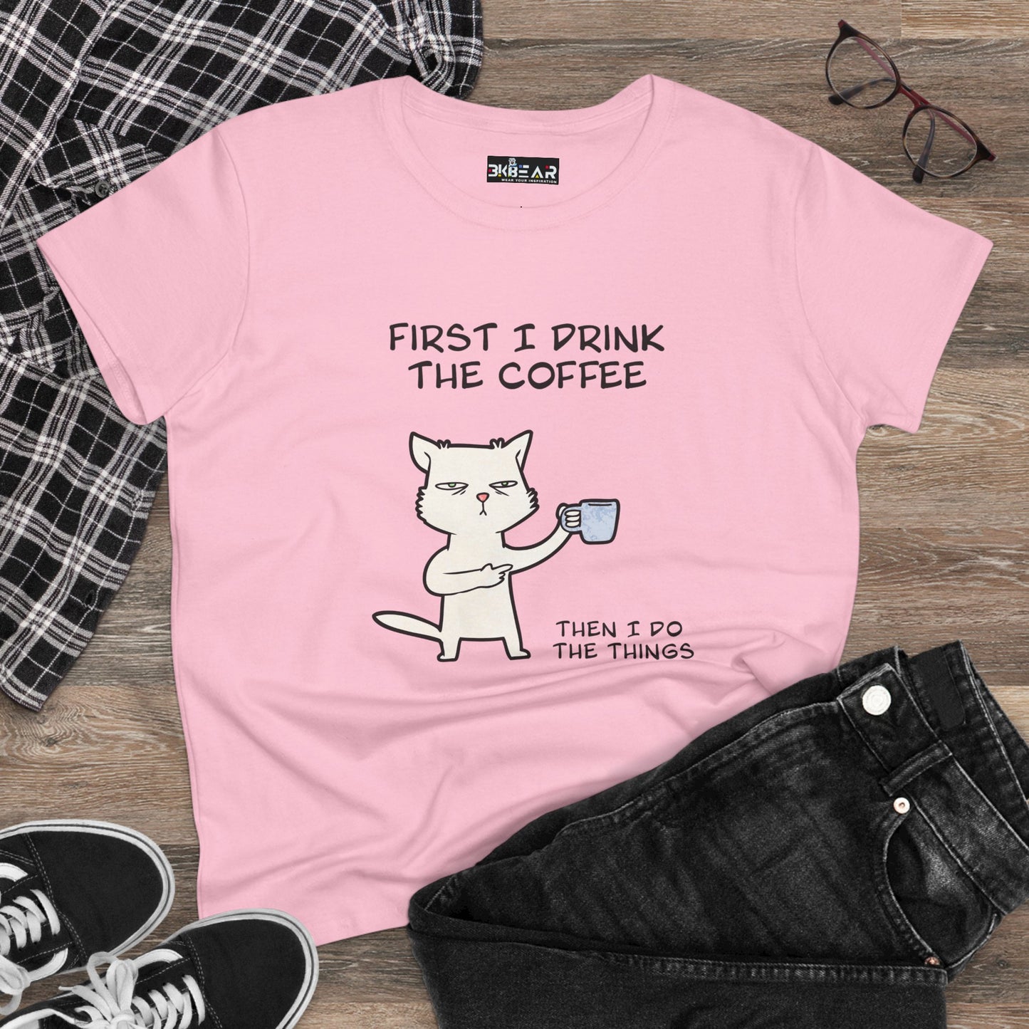 Pink cat coffee shirt with cartoon cat holding coffee cup and funny text laid flat with black jeans
