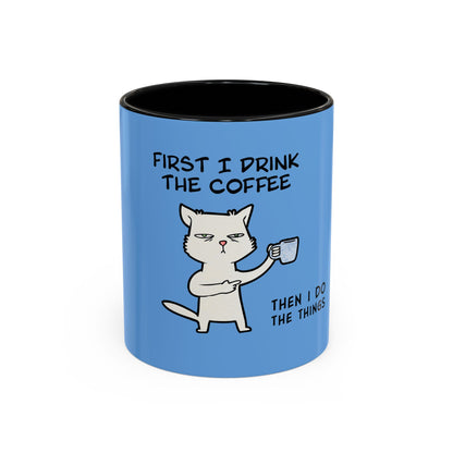 Blue coffee mug by Printify with a cat illustration and text saying first I drink the coffee