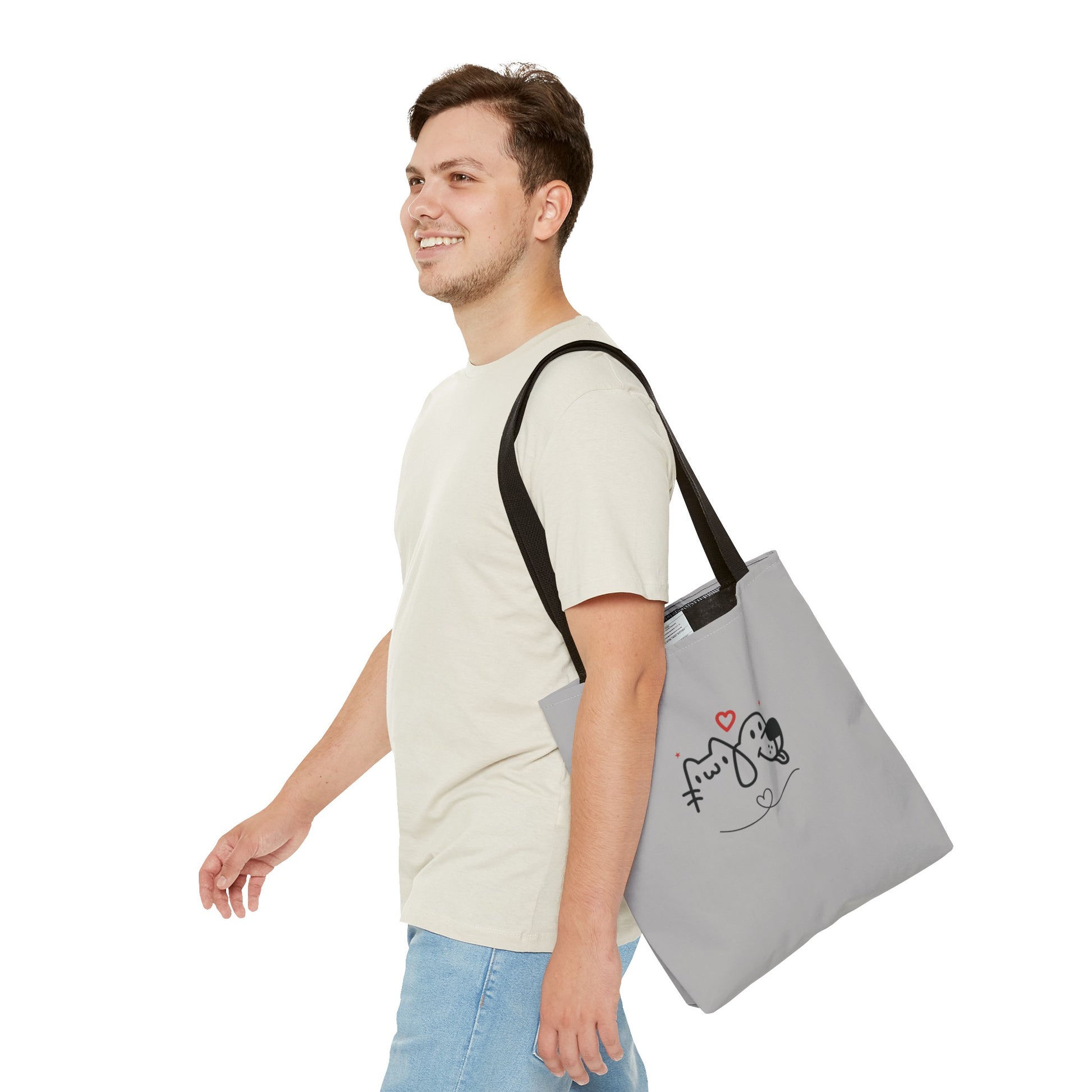 Man wearing a cute dog lover tote bag with black straps and a dog and cat design on a gray background