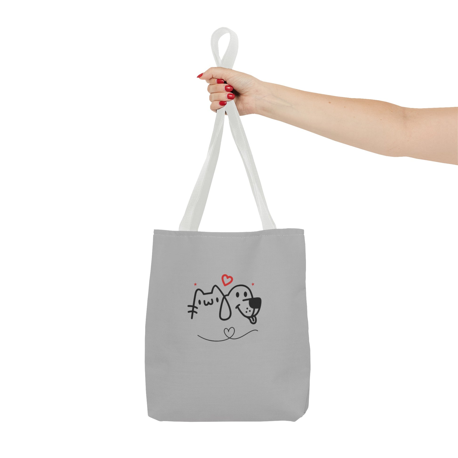 Hand holding a gray cute puppy tote bag with a simple dog and cat line art design and red hearts