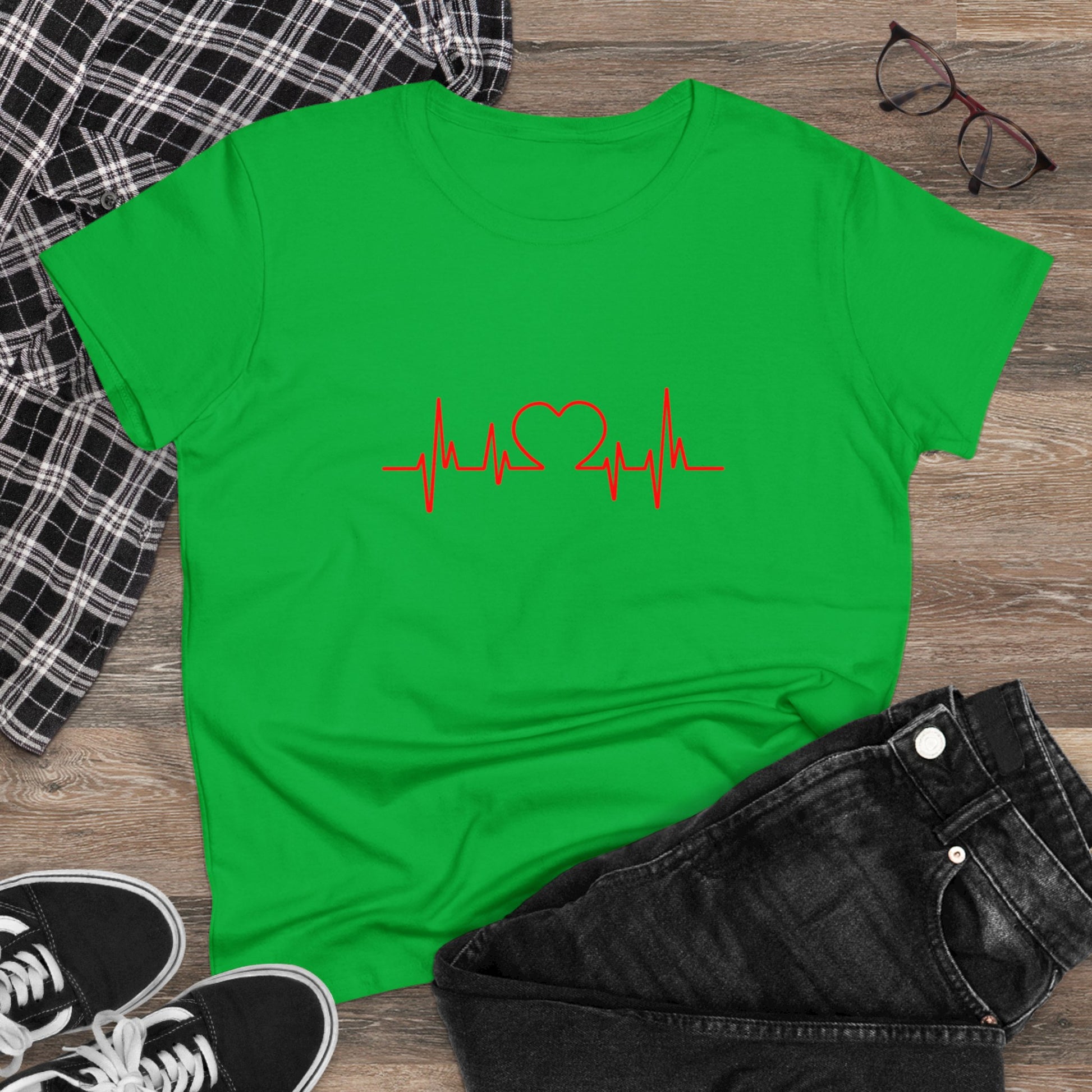 Green heartbeat graphic t-shirt with red heart and pulse line design laid flat with black jeans and sneakers