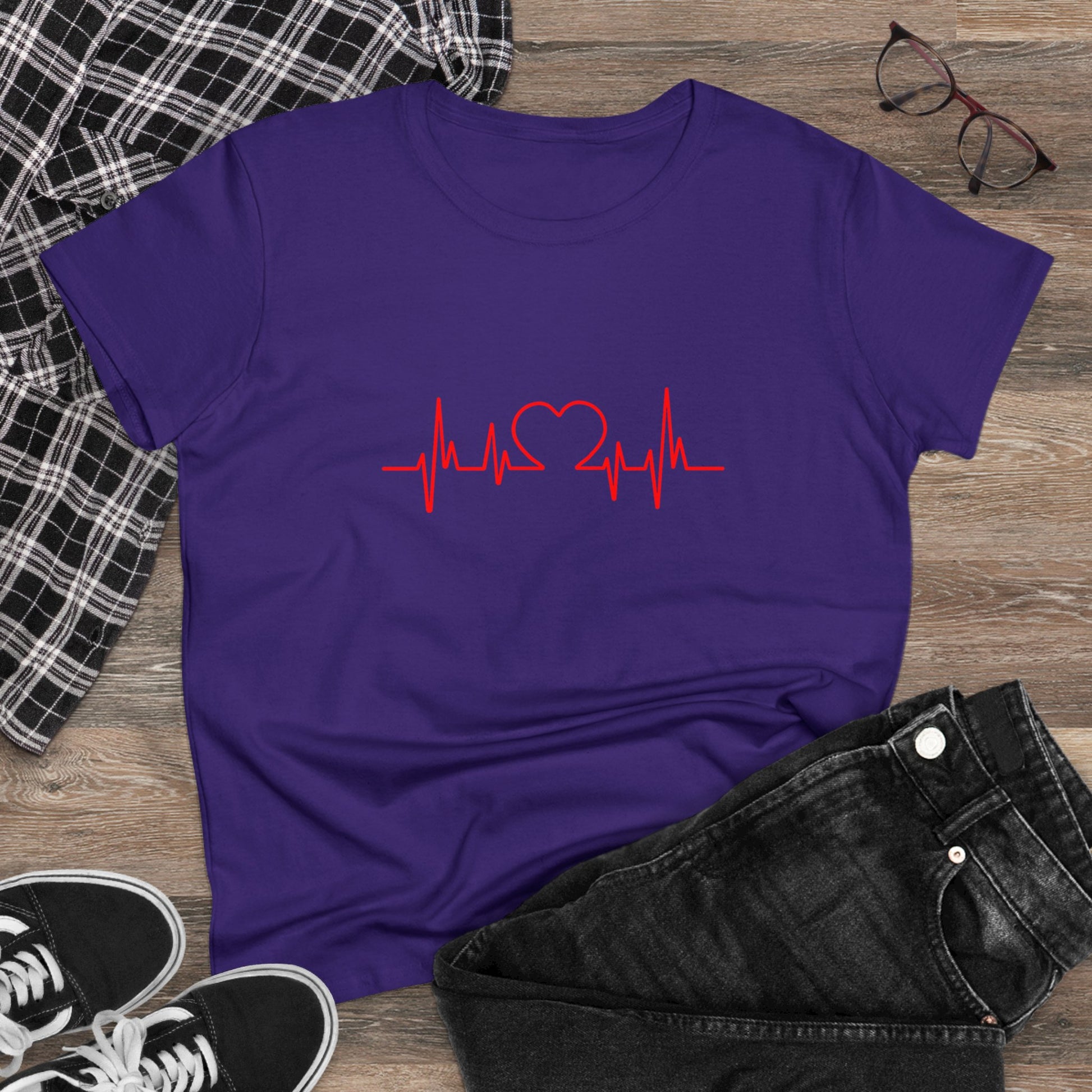 Purple heartbeat graphic t-shirt with red heart and pulse line displayed on wooden background