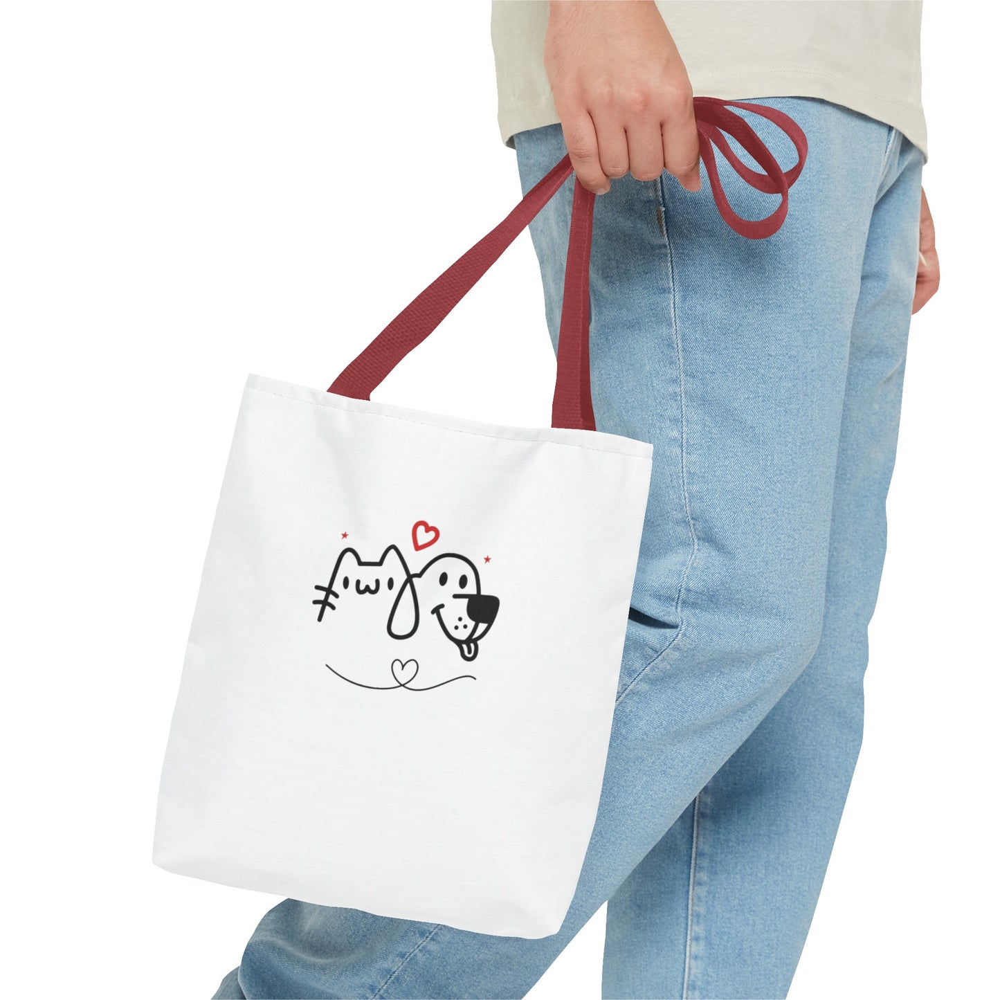 Person holding a white puppy love graphic tote bag with red handles featuring cute dog and cat design
