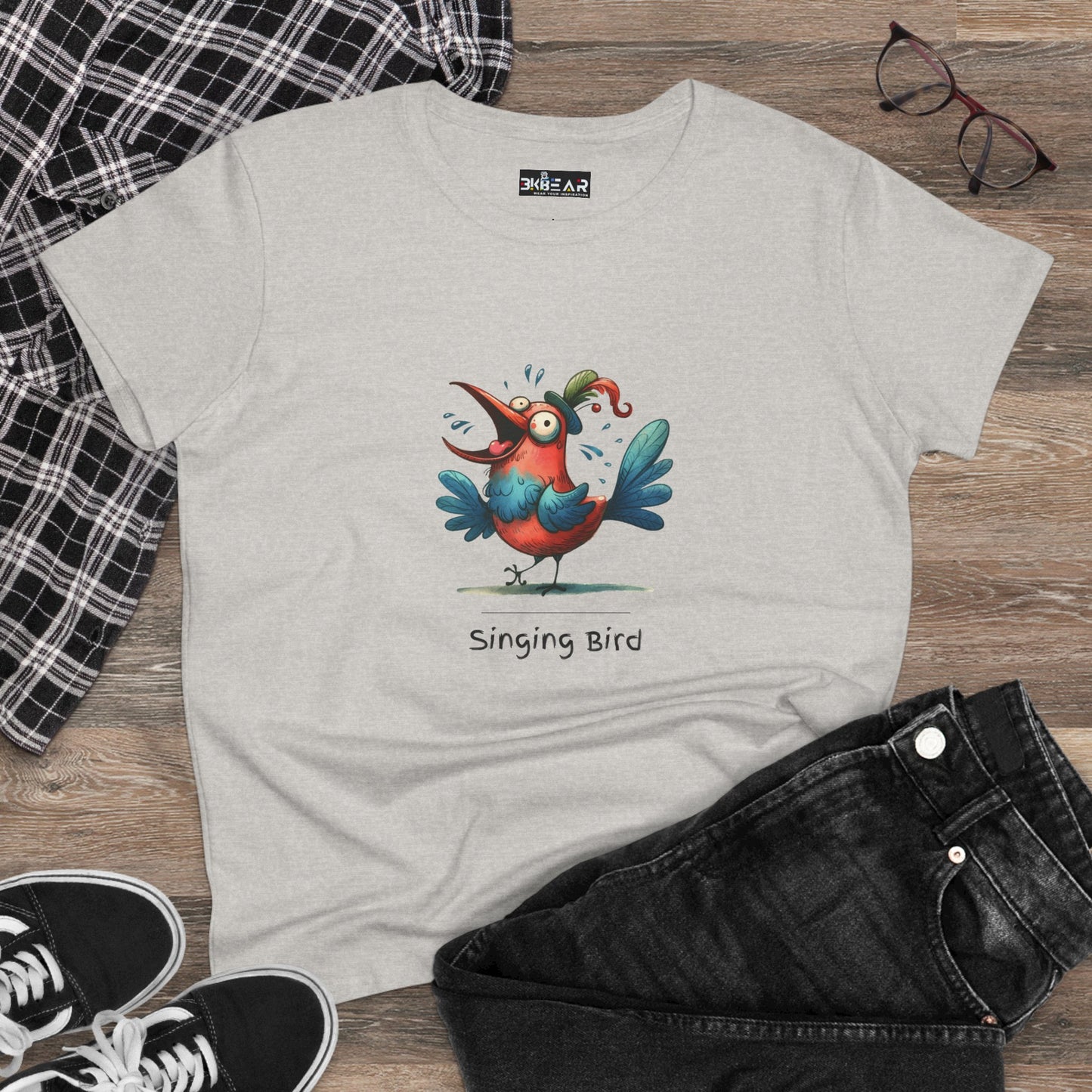 Light gray Printify singing bird shirt with colorful cartoon bird graphic and casual outfit on wooden floor