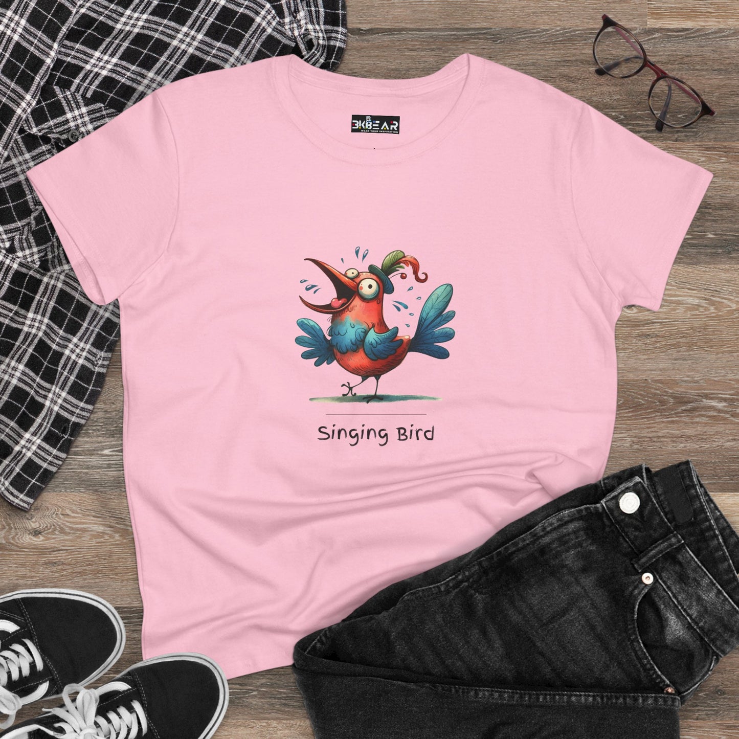 Pink singing bird shirt with colorful cartoon bird design laid flat with black jeans and sneakers