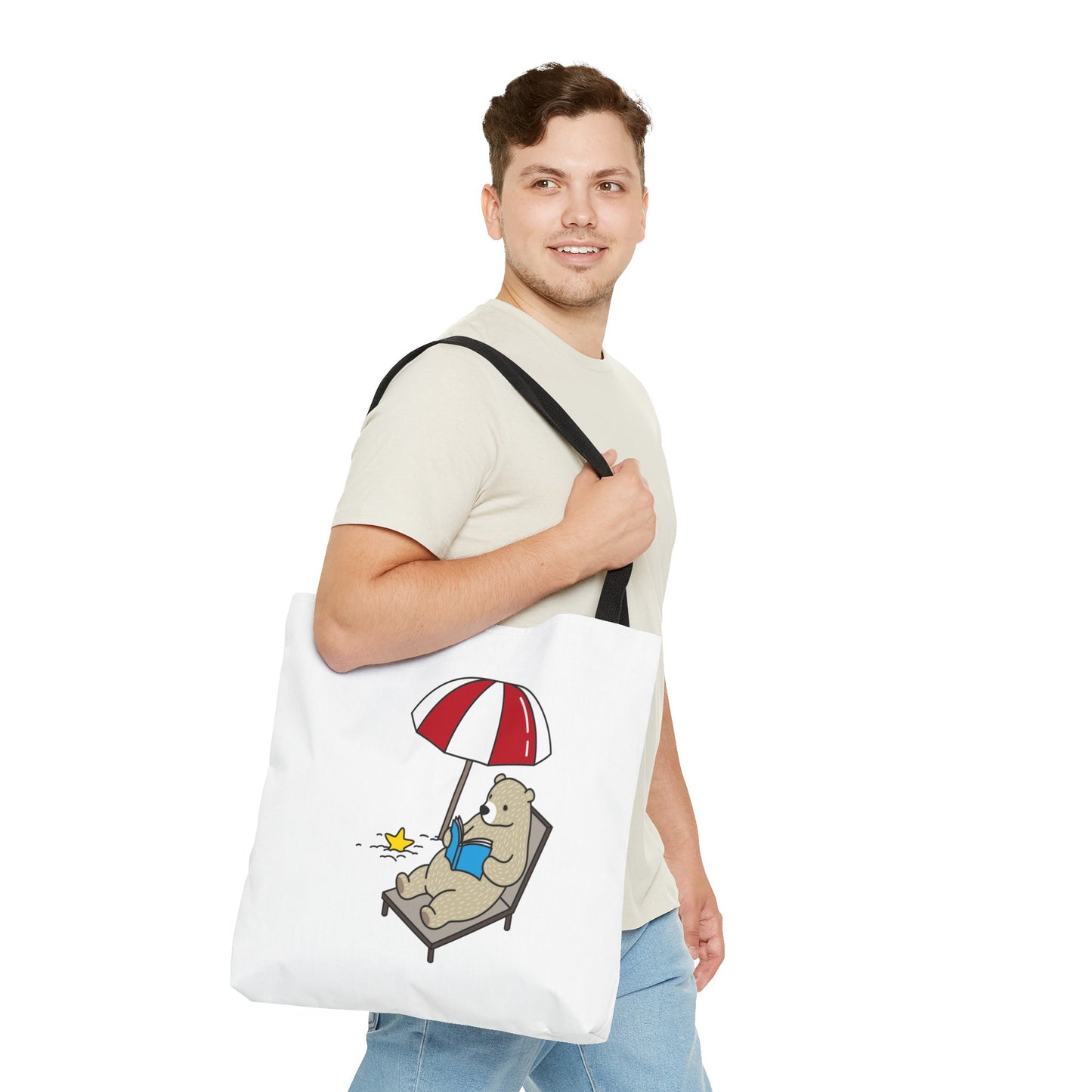 Man carrying a white summer beach tote with bear design sitting under an umbrella