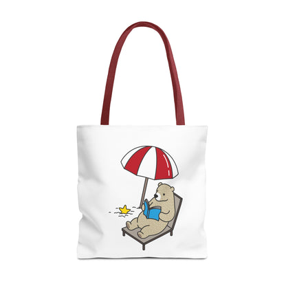 White summer beach tote with bear design lounging on chair under red umbrella reading a book
