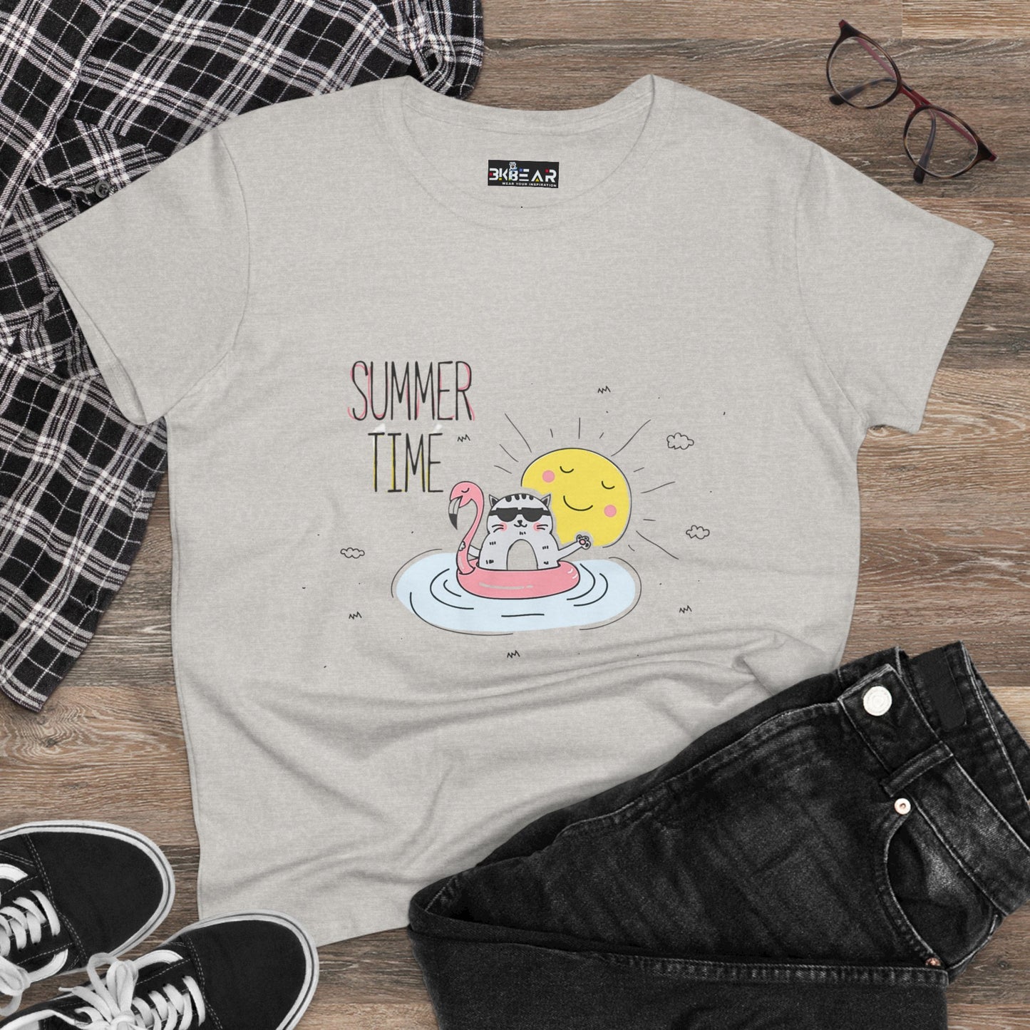 Light gray summertime cat tee with cute cat on flamingo float and sun graphic laid flat with black jeans and checkered shirt