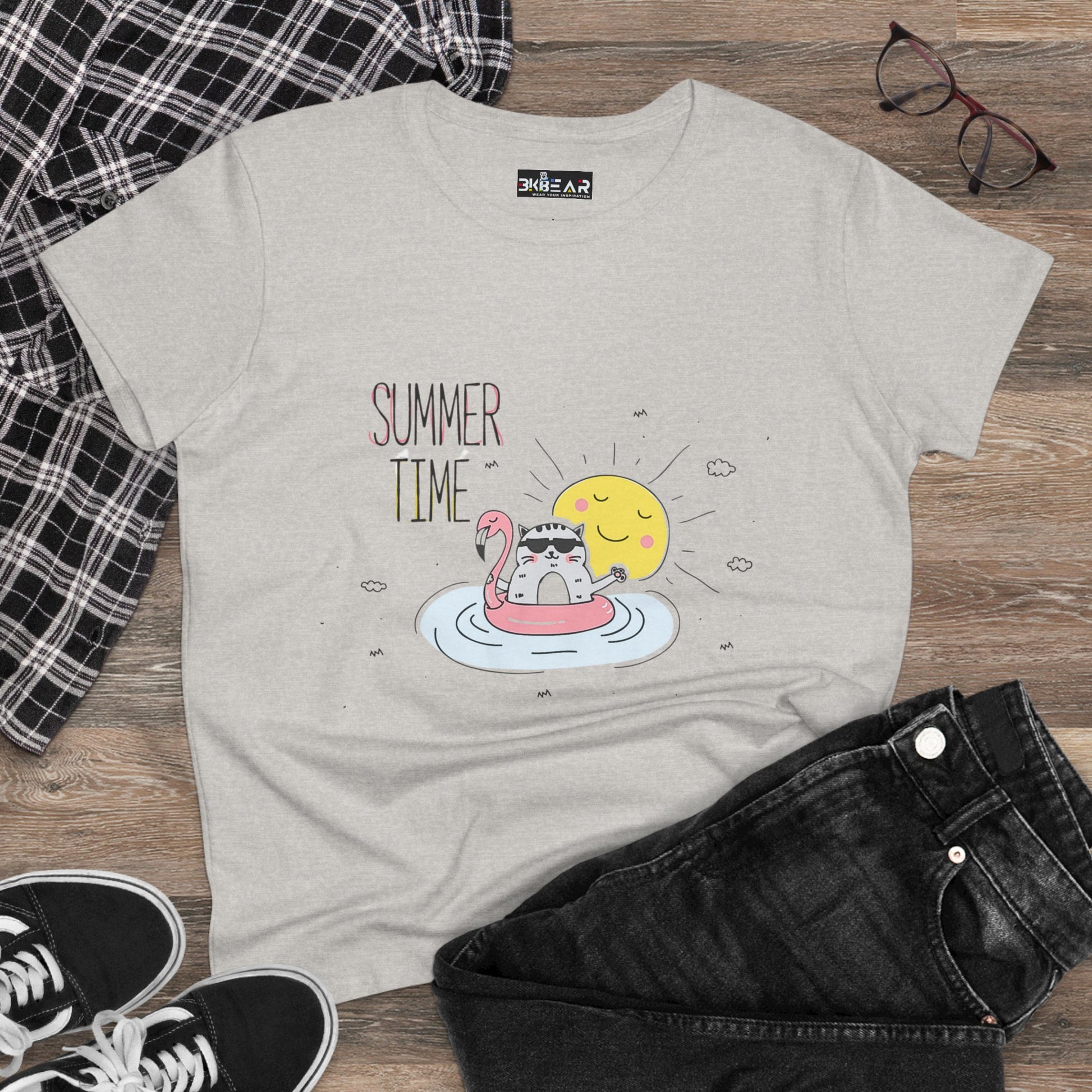 Light gray summertime cat tee with cute cat on flamingo float and sun graphic laid flat with black jeans and checkered shirt